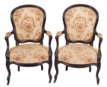 A pair of carved and ebonised mahogany and later upholstered open elbow chairs in George III style,