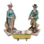 A pair of pearlware figures of a Hunter and Huntress on rustic mounds and square bases together