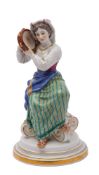 A Meissen figure of an Italian girl playing the tambourine wearing national costume and seated on