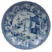 A Chinese blue and white lotus moulded dish painted with two ladies in a garden by a pavilion