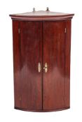 A George III mahogany bowfront hanging corner cabinet,