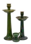 Two green glazed earthenware tall candlesticks and a similar jug,