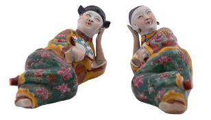 A pair of Chinese porcelain figures of a reclining male and female figure attired in colourful