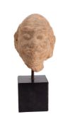 An Indian carved sandstone head of a moustachioed man with shaved head, furrowed forehead,