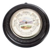 An Edwardian ebonised aneroid barometer the round dial with a landscape scene to the centre,