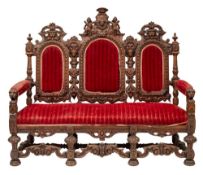 A Victorian carved oak and red velvet upholstered settee, in Carolean Revival style,