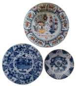A mixed lot of Dutch delftware comprising four blue and white chargers and a plate variously