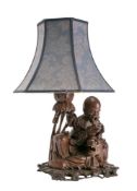 A Chinese carved hardwood table lamp depicting an Immortal seated with a tiger and reading a book,