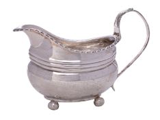 A Georgian unhallmarked cream jug of barge shape with gadrooned rim,