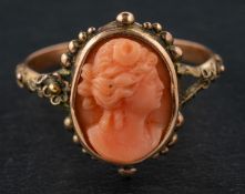 A carved coral cameo ring, depicting the head of a lady in profile, within cannetille surround,