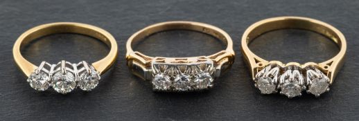 Three, round brilliant-cut diamond, three-stone rings, including an 18ct gold ring,
