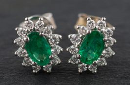 An 18ct gold, pair of oval, mixed-cut emerald and diamond cluster ear studs, total emerald weight 0.