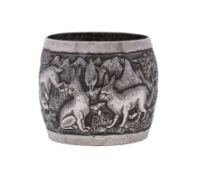 A Burmese silver embossed serviette ring decorated with birds and animals in a naturalistic setting.
