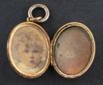 An Edwardian, oval locket pendant, engraved with heart-shaped and foliate decoration,