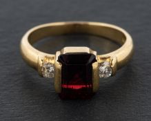 An 18ct gold, octagonal, step-cut garnet and round, brilliant-cut diamond, three-stone ring,