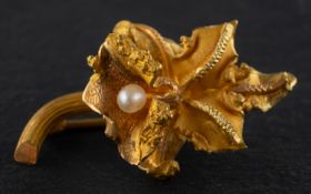 An orchid brooch, set with a seed pearl, stamped '18K', total length ca. 2.8cm, total weight ca. 3.