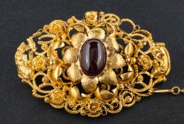 A cabochon-cut garnet, openwork brooch, with applied floral decoration, length ca.