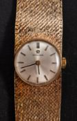 Omega, a ladies 9ct gold wristwatch the round dial with raised black and gold baton numerals,