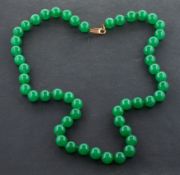 A jadeite bead necklace, diameter of beads ca. 9.7-10mms, the clasp stamped '9K', total length ca.