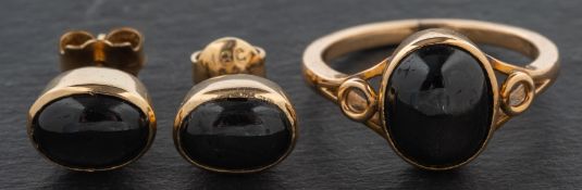 An oval, cabochon-cut, black star sapphire ring and pair of ear studs,