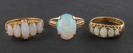 Three oval, cabochon-cut opal rings, including one single-stone ring, estimated opal weight ca. 1.