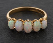 An oval, cabochon-cut opal, five-stone ring, stamped '18CT', length of ring head ca. 1.