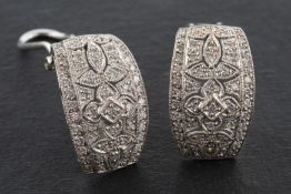 A pair of half hoop, openwork, diamond earrings, total estimated diamond weight ca. 1.