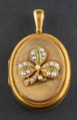 An oval, locket pendant, with probably peridot and seed pearl clover leaf design,