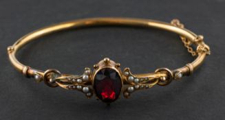 An oval, mixed-cut garnet and seed pearl, hinged bangle, estimated garnet weight ca. 4.