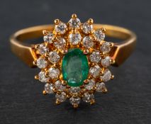 An 18ct gold, oval, mixed-cut emerald and round, brilliant-cut diamond cluster ring,