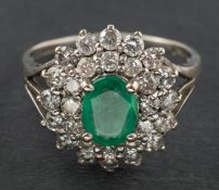 An 18ct gold, oval, mixed-cut emerald and round, brilliant-cut diamond cluster ring,