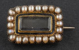 A 19th century mourning brooch, the glass centrepiece with black enamel and seed pearl surround,