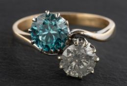 A round, brilliant-cut diamond and round, mixed-cut blue zircon cross-over ring,