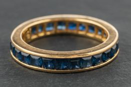 A step-cut, sapphire eternity ring, stamped '750', ring size O, total weight ca. 4.5gms.