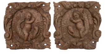 A pair of 18th century carved oak panels of putti riding dolphins: within relief carved scroll
