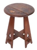 An Arts and Crafts oak circular occasional table on four tapered and splayed standard supports with