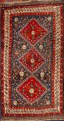 A Quashgai rug: the indigo field with triple red hooked lozenge medallions,