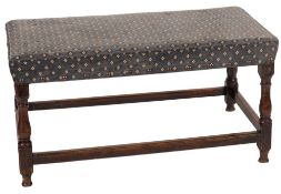 An oak and upholstered long stool in 17th century taste,