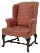 A stained mahogany and upholstered wing back armchair in George II style,