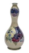 A William Moorcroft double gourd vase tube lined and decorated in the Pansy design on a green