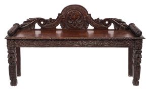 A late Victorian carved oak bench seat, the shaped and domed back with acanthus,