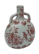 A Chinese porcelain moon flask painted front and verso in copper-red with a song bird amongst