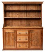 A pine kitchen dresser, early 20th century; the plate rack with moulded cornice above two shelves,