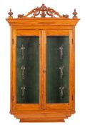 A pine hanging cabinet of small size, with pierced and carved foliate cresting and urn finials,
