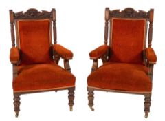 A pair of Victorian carved oak library armchairs, the pediment with carved lion motif,