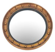 A giltwood and gesso circular convex wall mirror in the Regency taste, the plate within an ebonised,