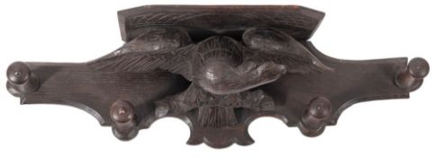 A carved and stained oak bracket and peg rail,