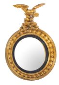 A Regency giltwood and gesso circular convex mirror surmounted by a figure of an eagle with