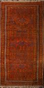 An Afghan rug the rust field with triple lozenge medallions and geometric designs,