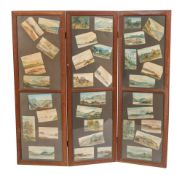 An oak three fold screen with inset watercolour studies of landscapes,